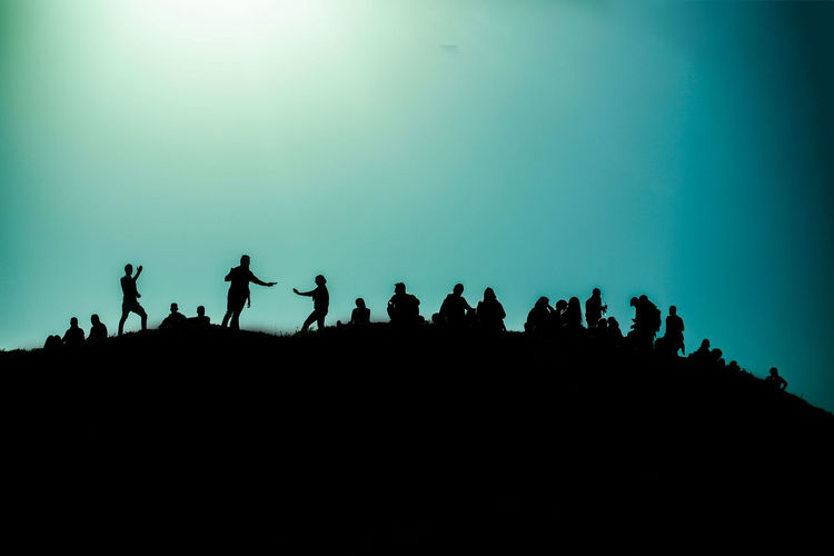 Silhouette people against clear blue sky
