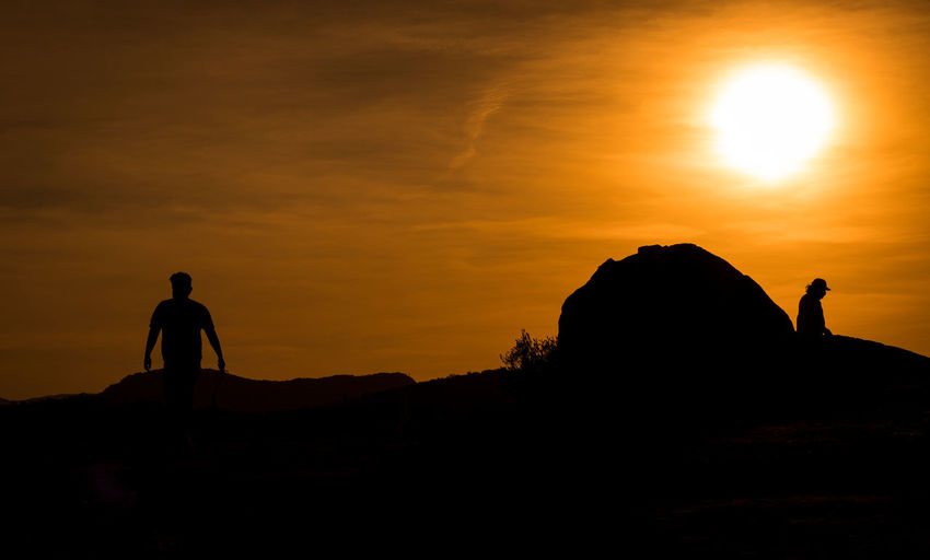 Hiking - silhouette man standing on rock against sky during sunset