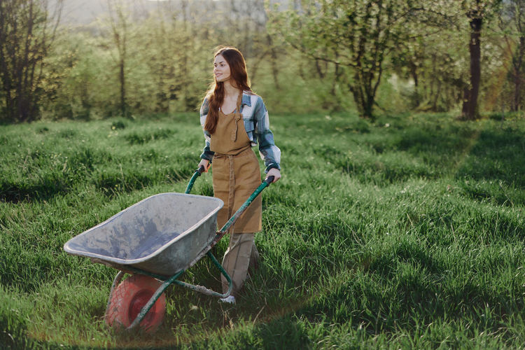 Young farmer with wheelbarrow walking n farm