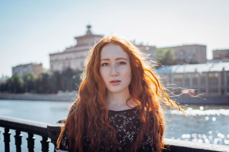 Portrait of beautiful young woman against river