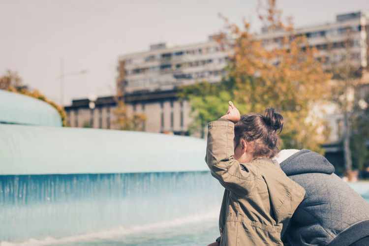 Playful siblings standing by fountain in city