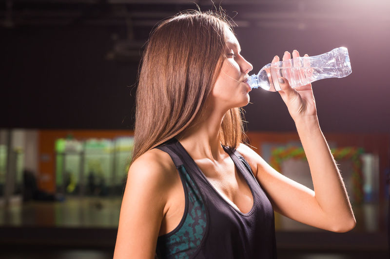 Midsection of woman drinking water bottle
