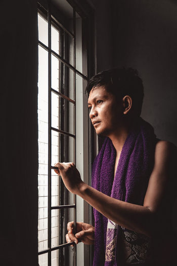 Side view of young man looking away at home