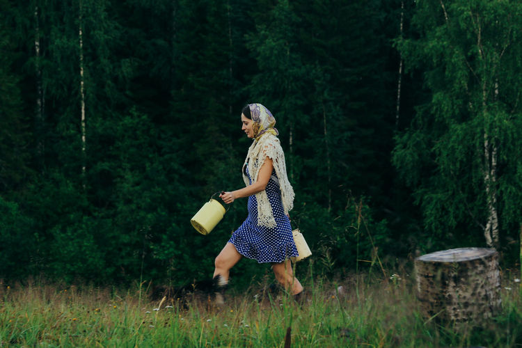 Rustic young woman in blue polka dot dress with cans