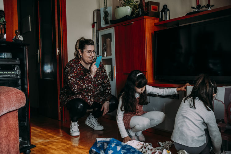 Mother recording with smartphone her daughters opening gifts