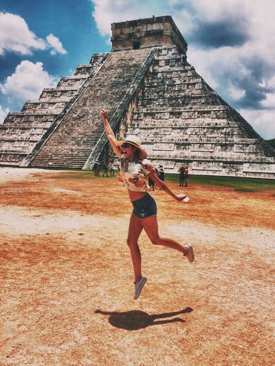 Full length of happy woman jumping against chichen itza