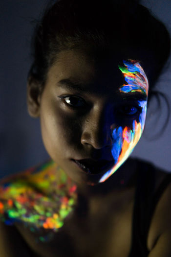 Close-up portrait of young woman with paint on face and shoulder