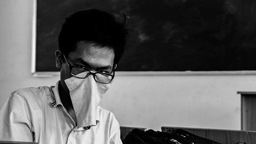Portrait of teenage boy with fabric on face in classroom