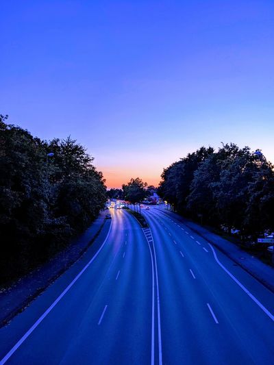 Diminishing perspective of road against clear blue sky during sunset