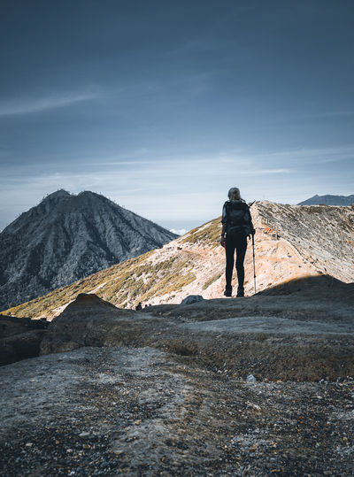 Rear view of woman walking on landscape against mountain