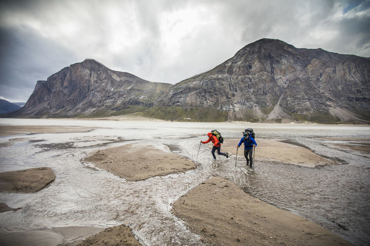 Two backpackers navigate a series of river crossings in akshayak pass