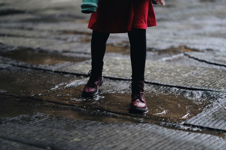 Low section of woman walking on puddle during rainy season