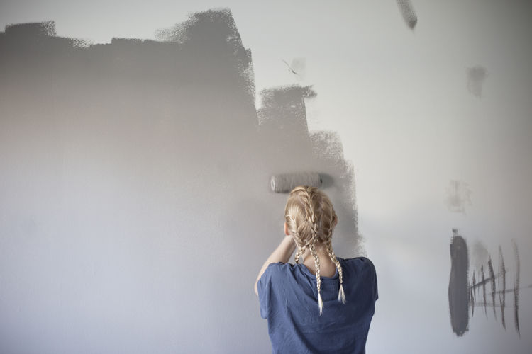 Rear view of girl painting wall