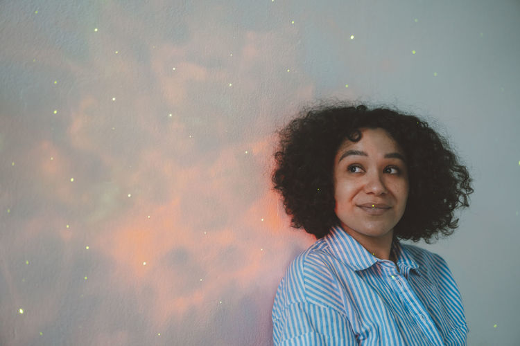 Smiling woman looking at astro light effect falling on wall
