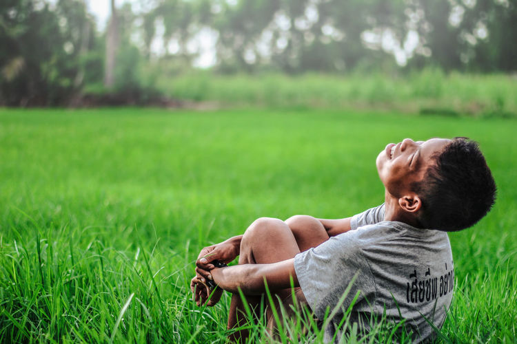Cheerful boy sitting on field