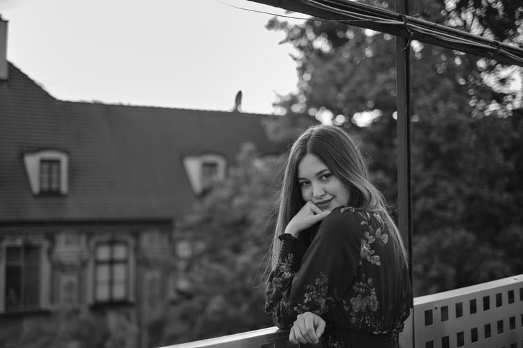 Portrait of young woman standing in balcony