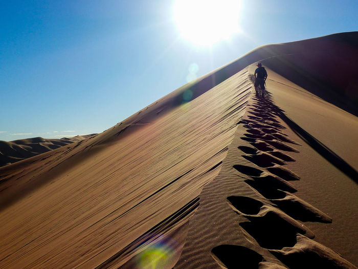 Man walking in desert against sky