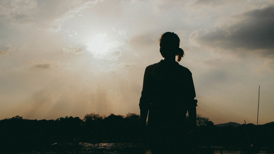 Silhouette girl standing against sky during sunset