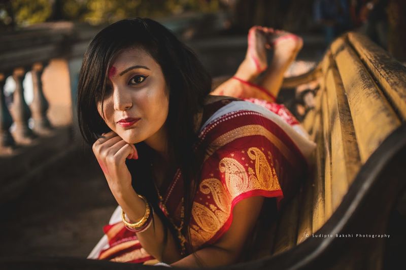 Portrait of woman in sari lying on bench at park