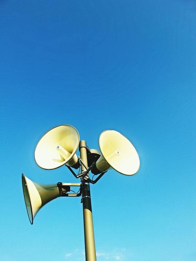 Low angle view of megaphone against clear blue sky