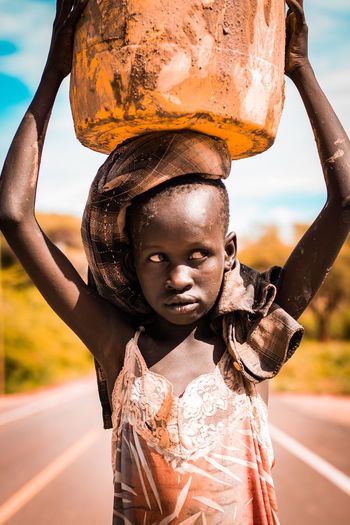 Teenage girl carrying container on head at road