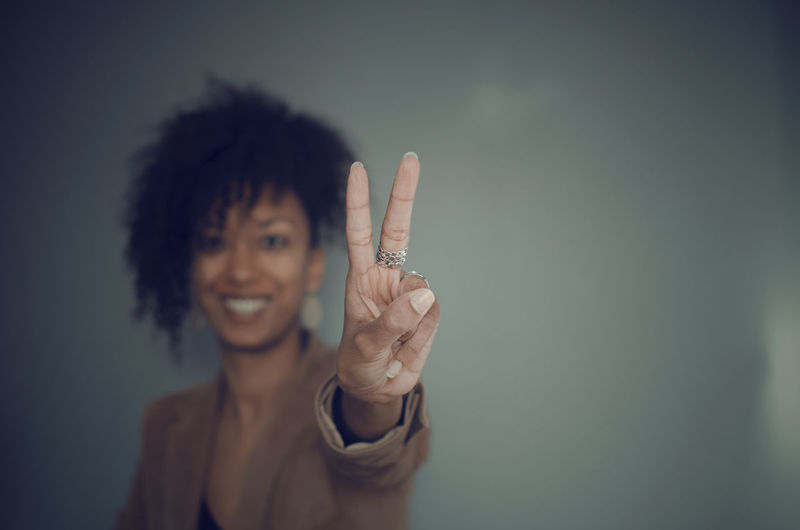 Selective focus on the hand with rings of a black woman showing two fingers as a gesture of victory