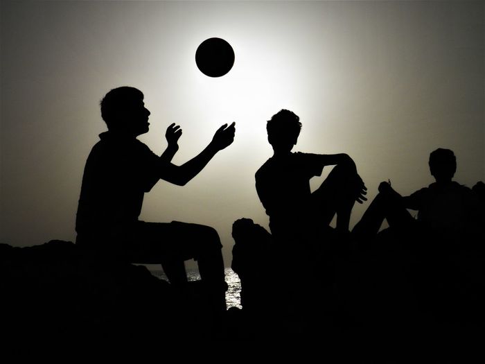 Silhouette people playing with ball against sky