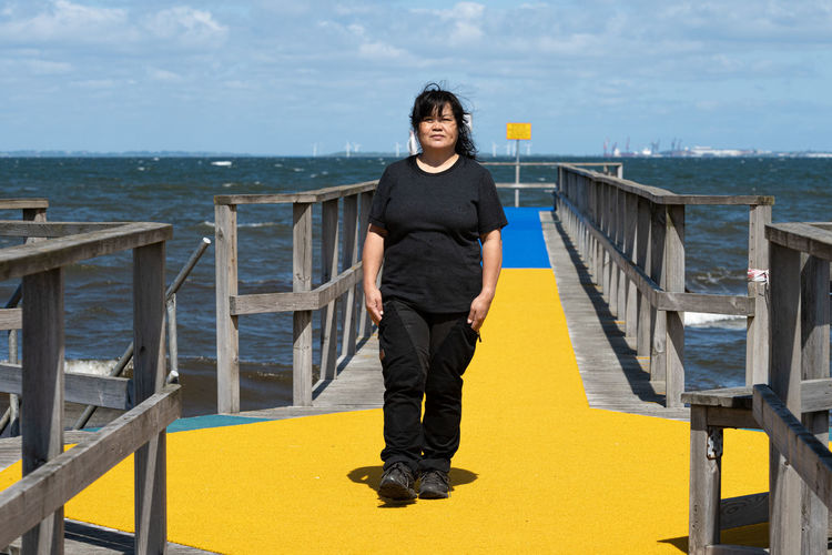 Full length of woman standing on pier against sea