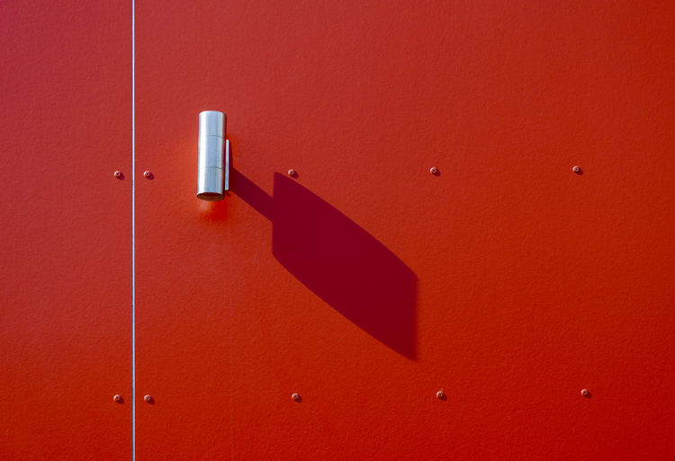 Modern outdoor light lamp with shadow on red wall on sunny day
