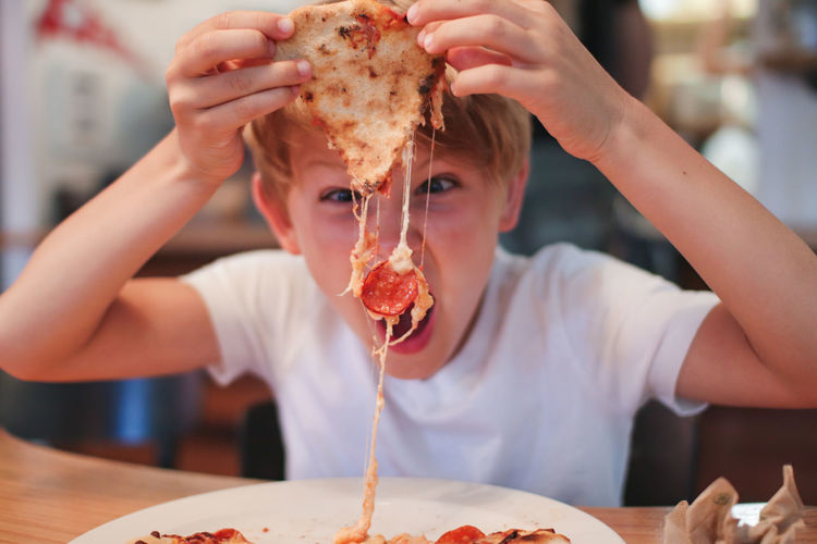 Portrait of boy eating pepperoni pizza