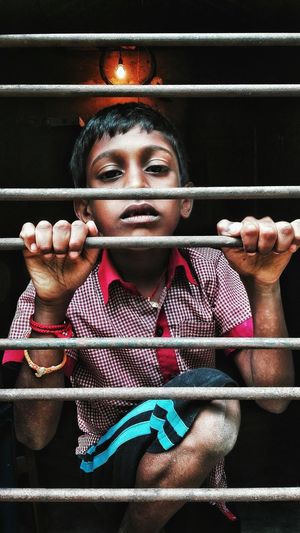 Portrait of boy holding security bars on window