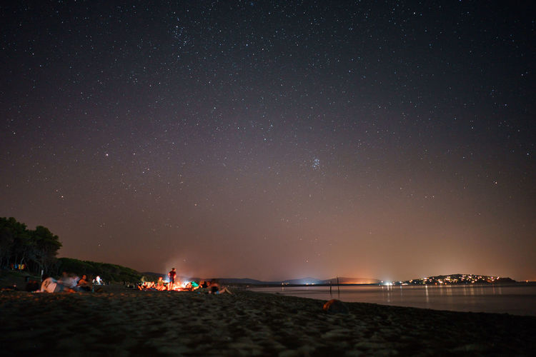 People on beach against sky at night
