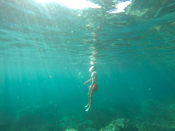 Side view of shirtless man swimming undersea