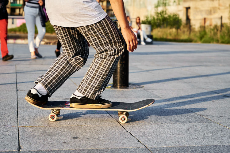 Skateboarder ride on skateboard at city street, close up