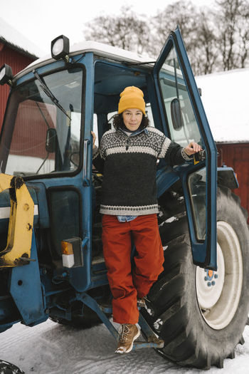 Full length of mature woman disembarking from tractor during winter