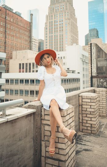Full length of woman sitting against buildings in city