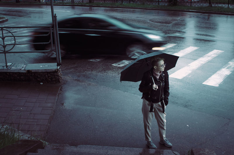 Full length of person with umbrella standing on wet street