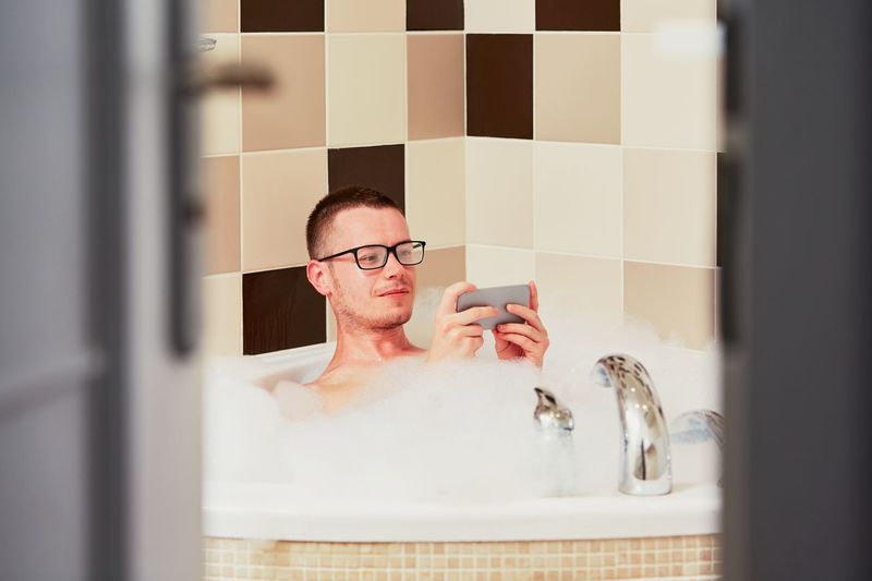 Man using smart phone in bathroom