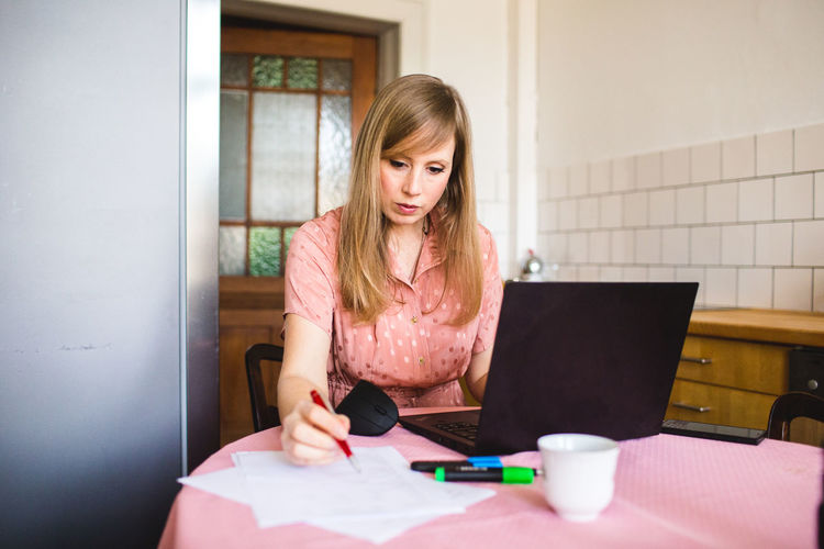 Young woman using mobile phone and notebook at home