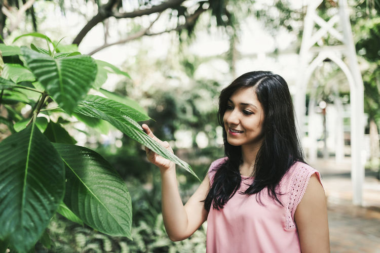 Close up of a beautiful agronomical engineer observing the plants in the greenhouse