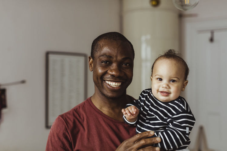 Portrait of smiling father and toddler son at home
