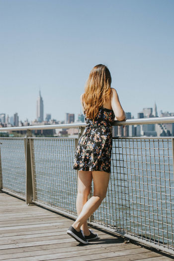 Rear view of woman standing by railing against river