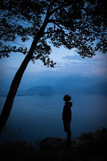 Man standing on mountain by lake against sky