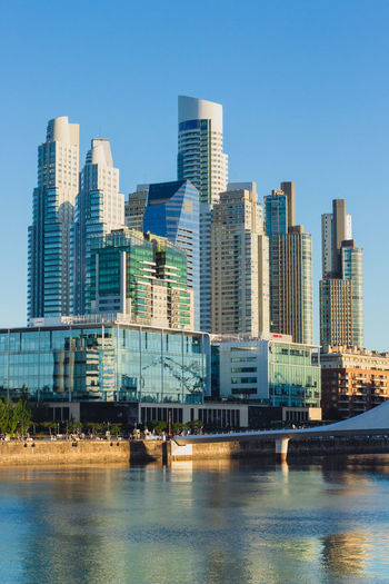 Modern buildings by river against clear sky at puerto madero, buenos aires