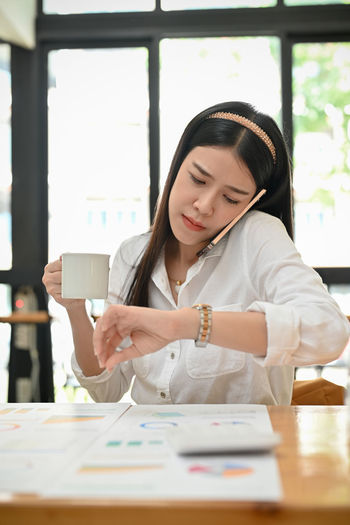 Portrait of young woman using mobile phone at office