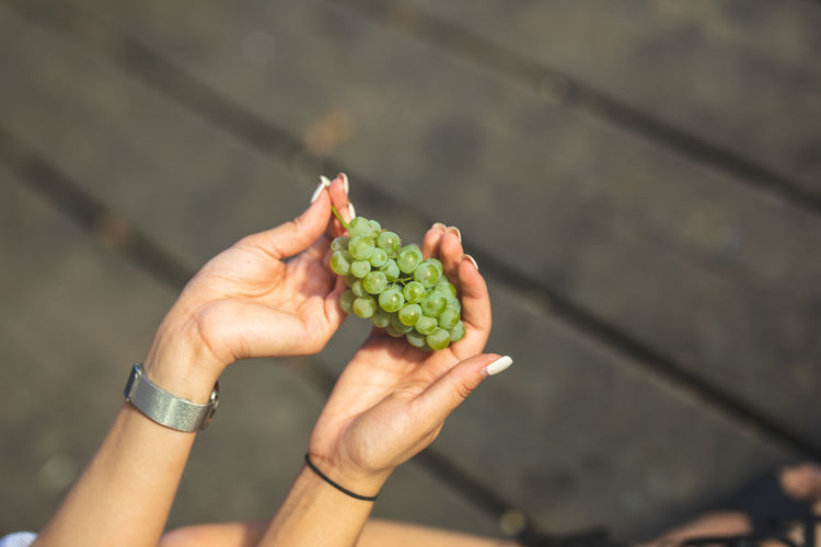 Cropped hands of woman having grapes on boardwalk