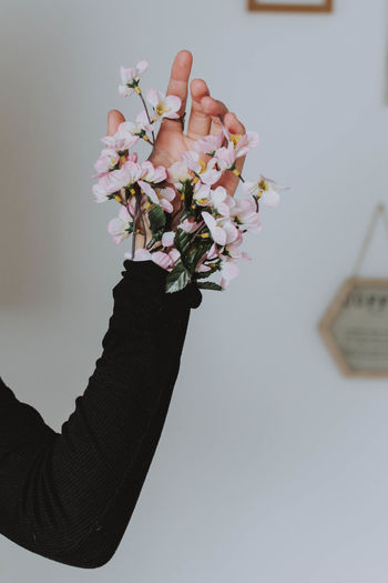Cropped hand of woman with flowers in home