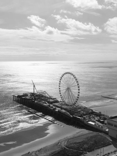 Scenic view of ferris wheel and sea against sky