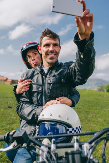Couple taking selfie while sitting on motorcycle