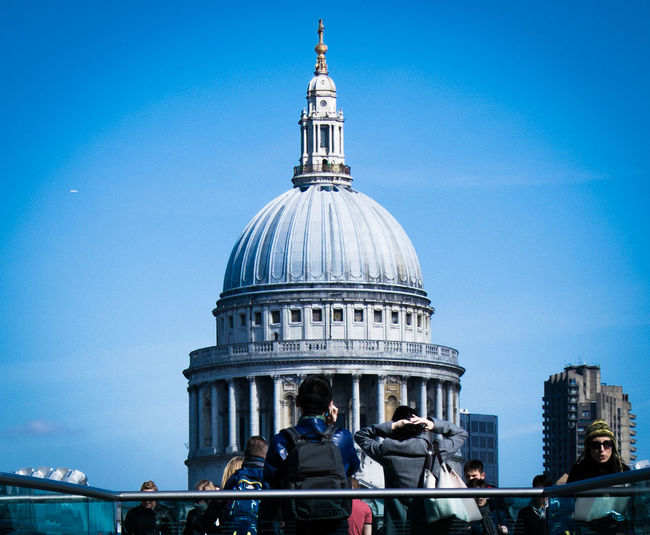 People on london millennium footbridge in front of st paul cathedral against sky